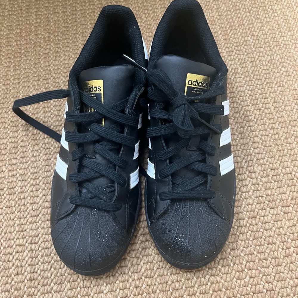 Adidas, the brand with the three straps, black tennis shoes never worn.